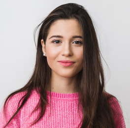 woman with dark hair wearing a pink pullover