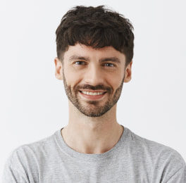 smiling man with dark hair wearing a gray t-shirt