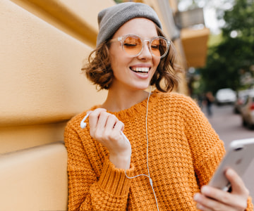 smiling woman with headphones using a mobile phone